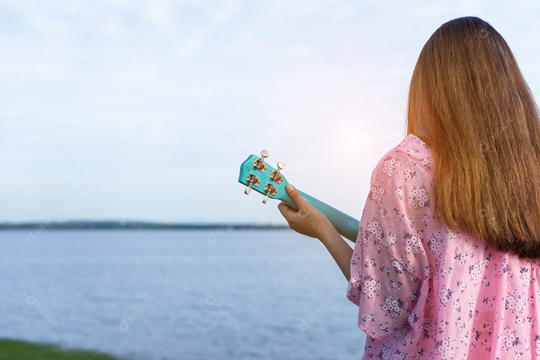 Mulher jovem segurando ukulele no lago