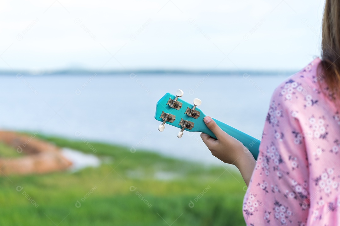 Mulher jovem segurando ukulele no lago