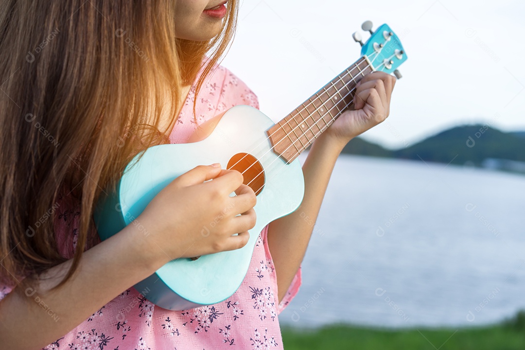 Mulher jovem segurando ukulele no lago