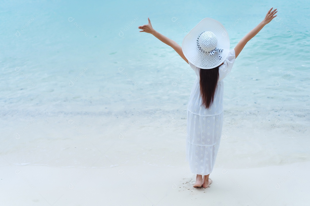 Mulher solteira andando na praia com vestido branco