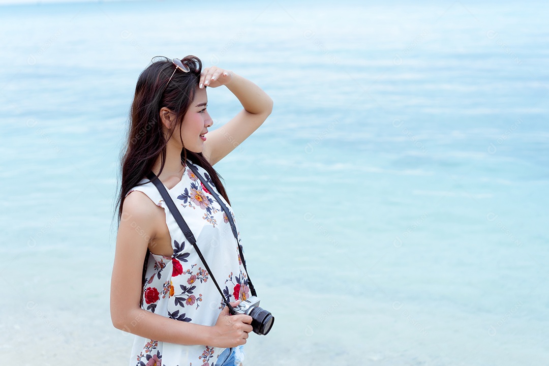 Mulher asiática tirando foto com câmera na praia