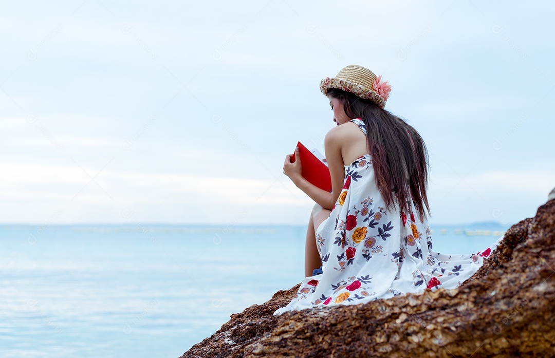 Mulher asiática lendo livro sozinha na praia