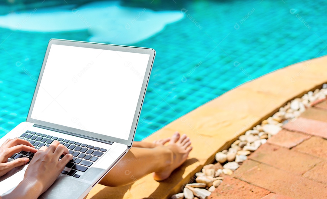 Mulher usando laptop na piscina na borda do resort com chapéu