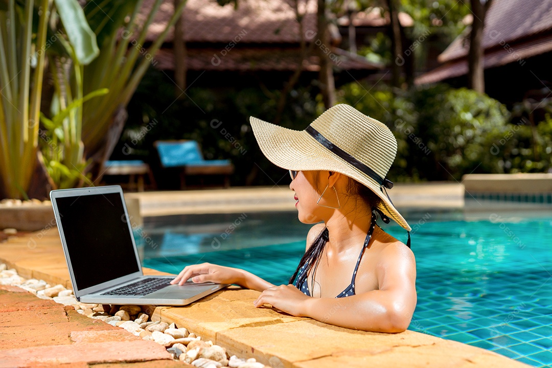 Mulher asiática de biquíni sexy na piscina usando computador portátil