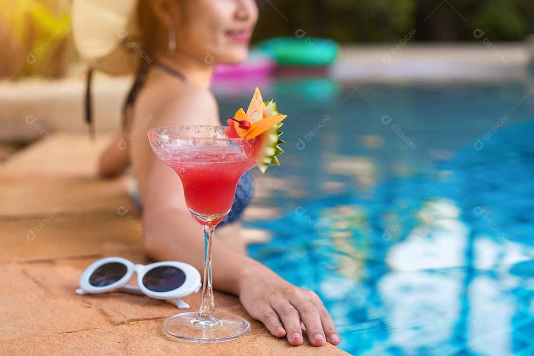 Mulher de biquíni na piscina relaxando com coquetel