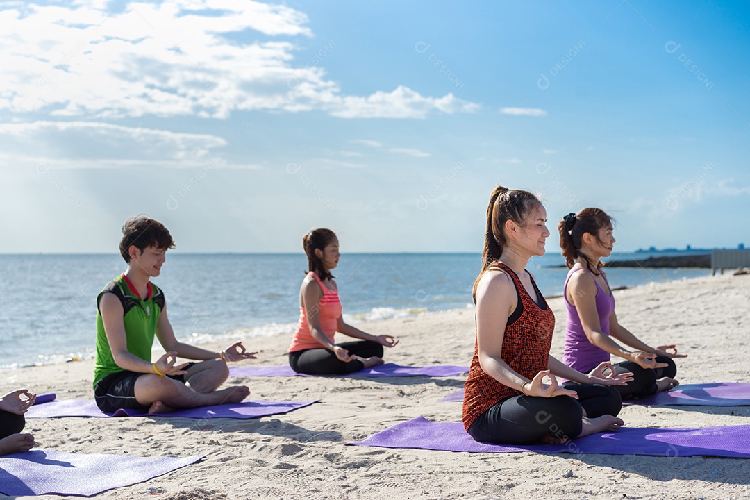 Grupo de jovens praticando ioga na areia da praia