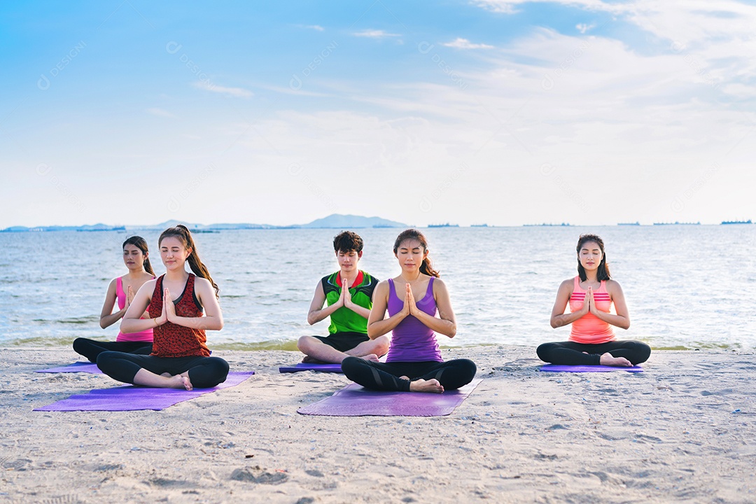 Grupo de jovens praticando ioga na areia da praia