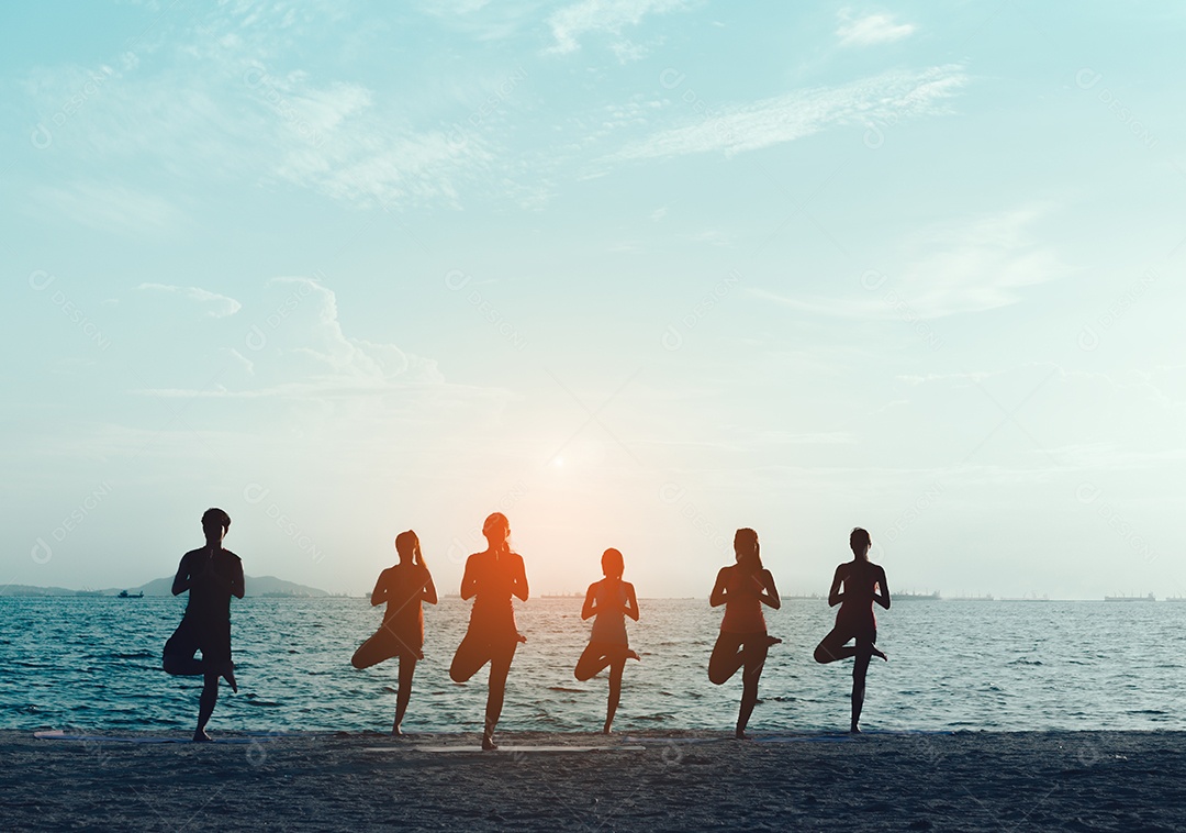 Grupo de jovens praticando ioga na areia da praia
