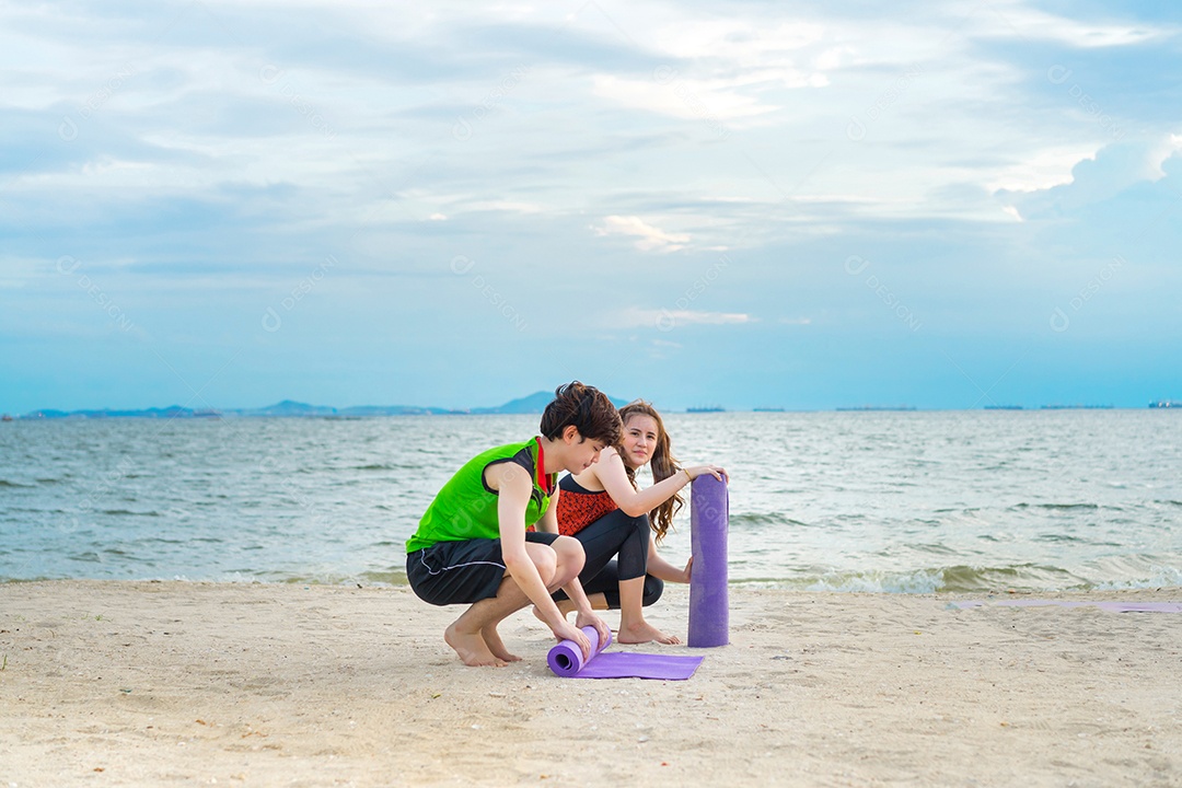 Grupo de jovens praticando ioga na areia da praia