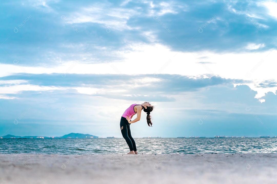 Jovem praticando ioga na praia á beira-mar