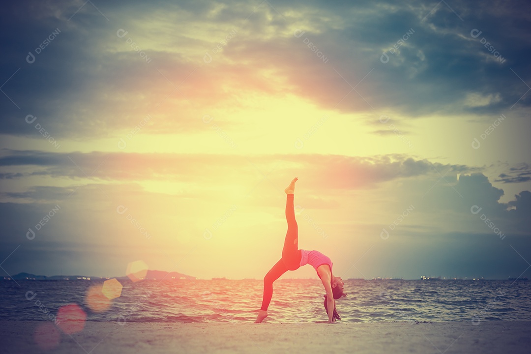Jovem praticando ioga na praia á beira-mar