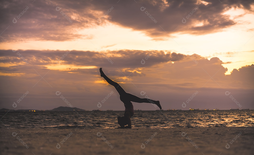 Jovem praticando ioga na praia á beira-mar