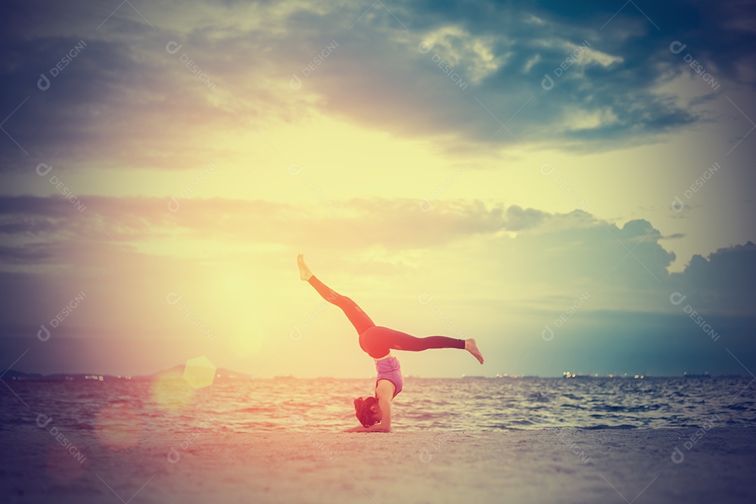 Jovem praticando ioga na praia á beira-mar