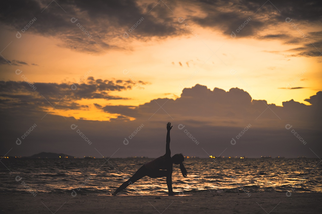 Jovem praticando ioga na praia á beira-mar