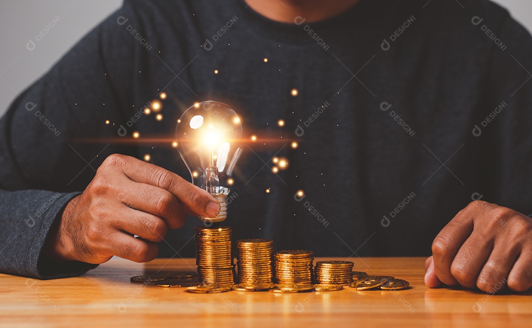 Mão segure a lâmpada na moeda de ouro economizando energia e conceito de dinheiro.