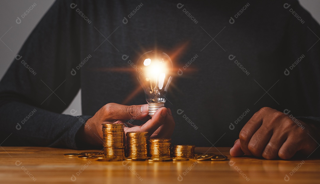 Mão segure a lâmpada na moeda de ouro economizando energia e conceito de dinheiro.