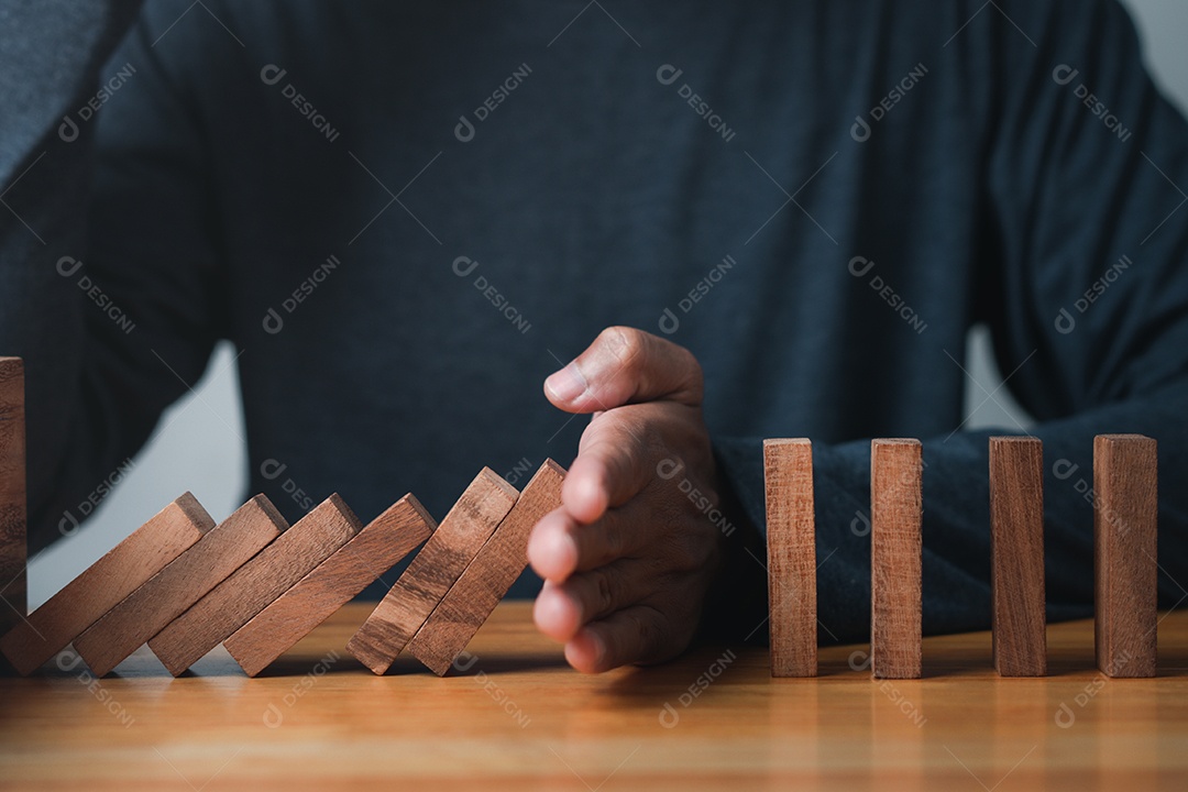 Mão parando o efeito de crise de negócios dominó ou conceito de proteção de risco