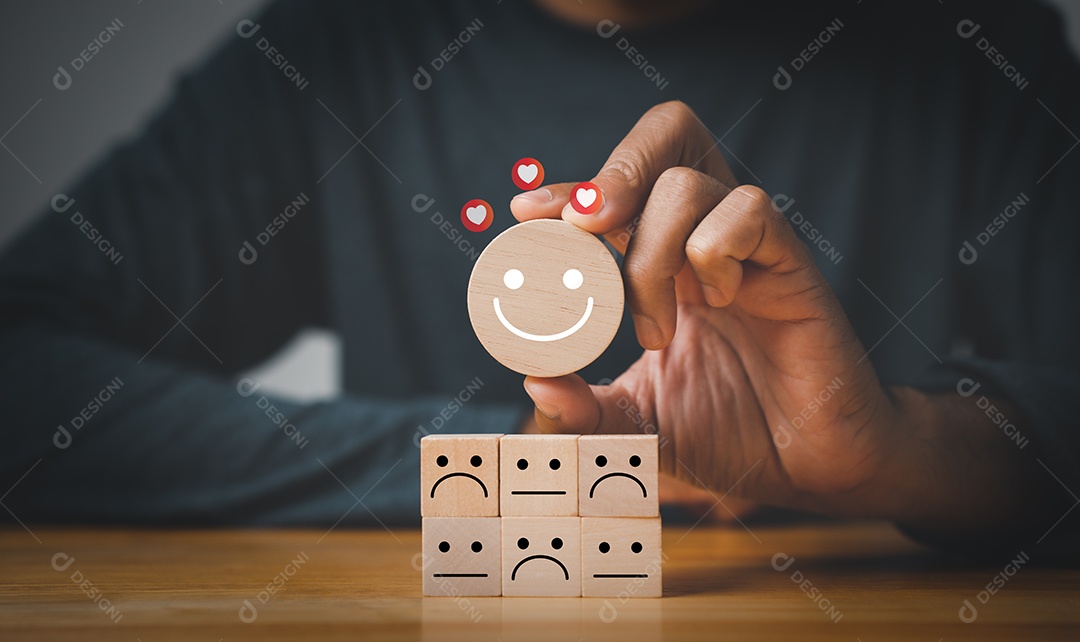 Conceito de pesquisa de satisfação. Mão de um empresário escolhe um rosto sorridente no cubo de bloco de madeira.