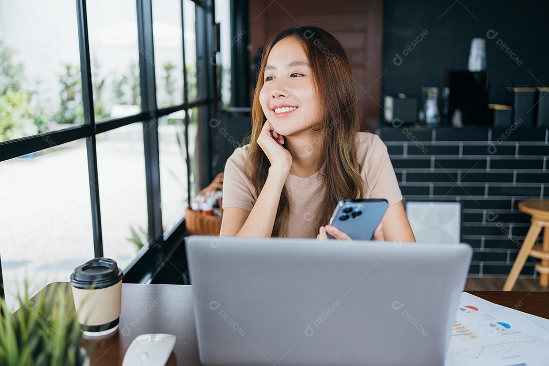 Mulher asiática freelancer freelancer sorrindo para ela trabalhando com laptop e smartphone