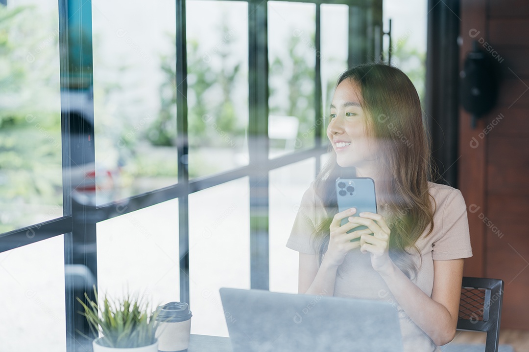 Mulher asiática freelancer freelancer sorrindo para ela trabalhando com laptop e smartphone