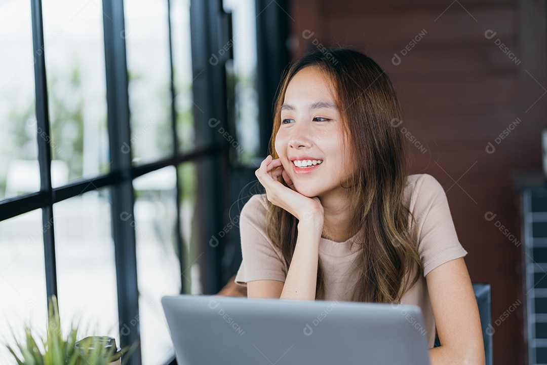 Mulher asiática freelancer freelancer sorrindo para ela trabalhando com laptop e smartphone