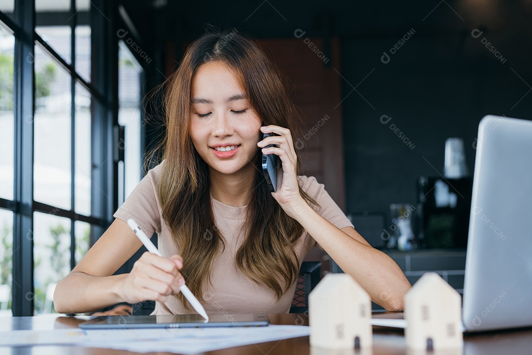 Mulher asiática freelancer freelancer sorrindo para ela trabalhando com laptop e smartphone