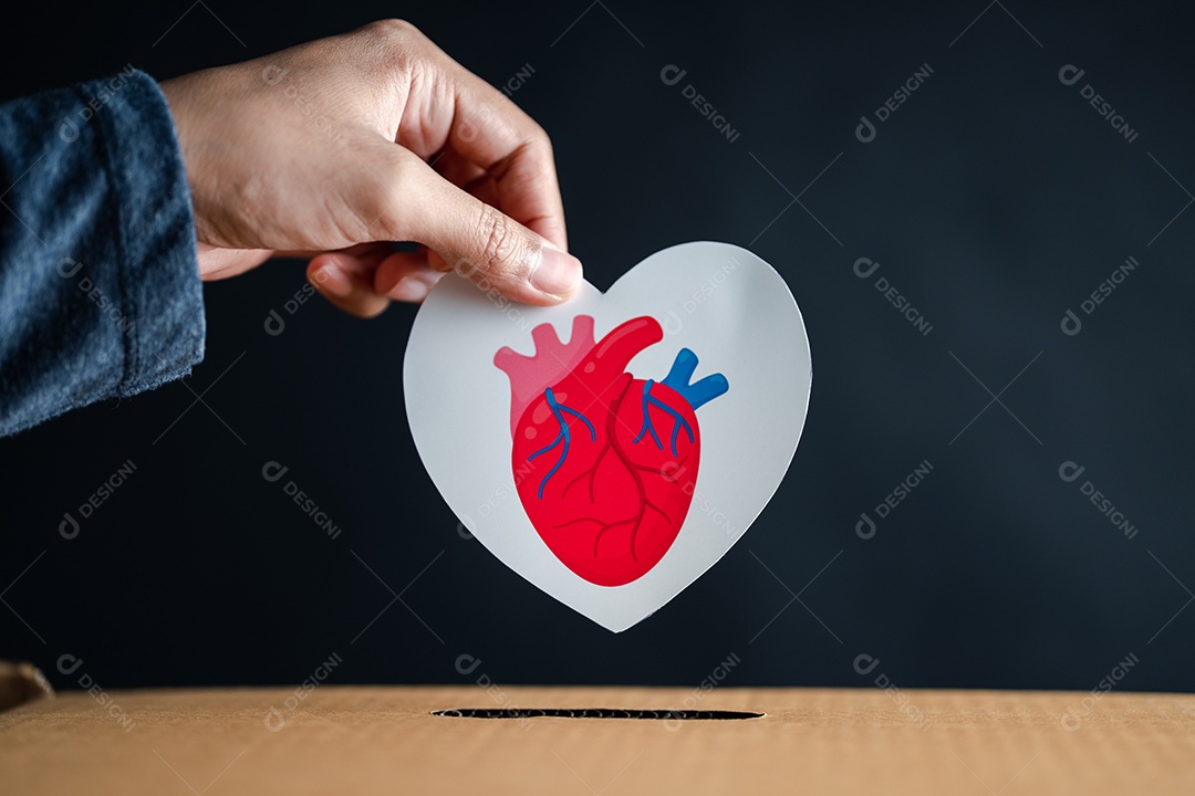 As mãos soltam o coração vermelho na caixa de doação.