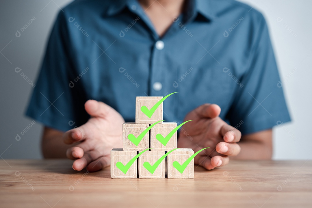 Empresário empilhando ícone correto verde que em bloco de madeira