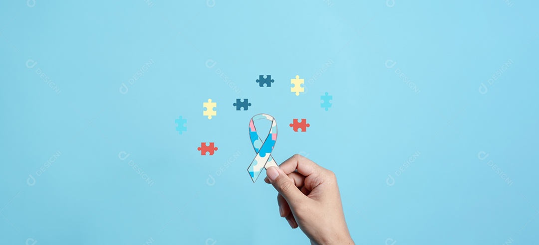 Mão segurando o quebra-cabeça da fita, símbolo de quebra-cabeça colorido de conscientização para o apoio à família do transtorno do espectro do autismo.