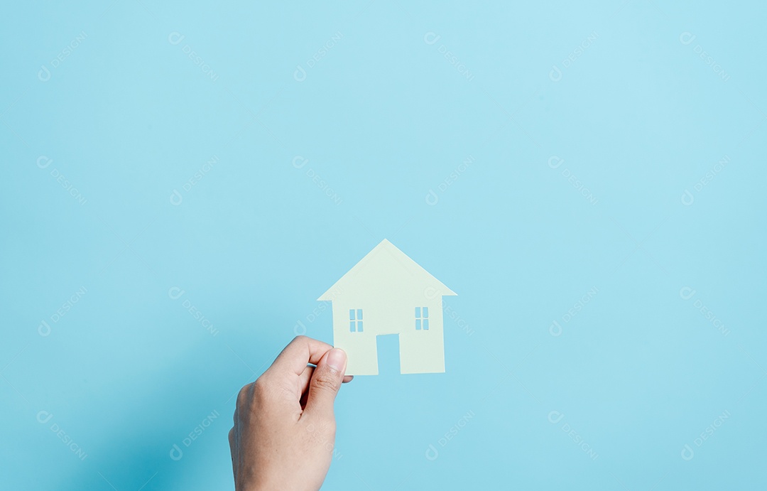 Mão segurando o corte de papel da casa, casa da família, habitação sem-teto, crise hipotecária e seguro de proteção residencial