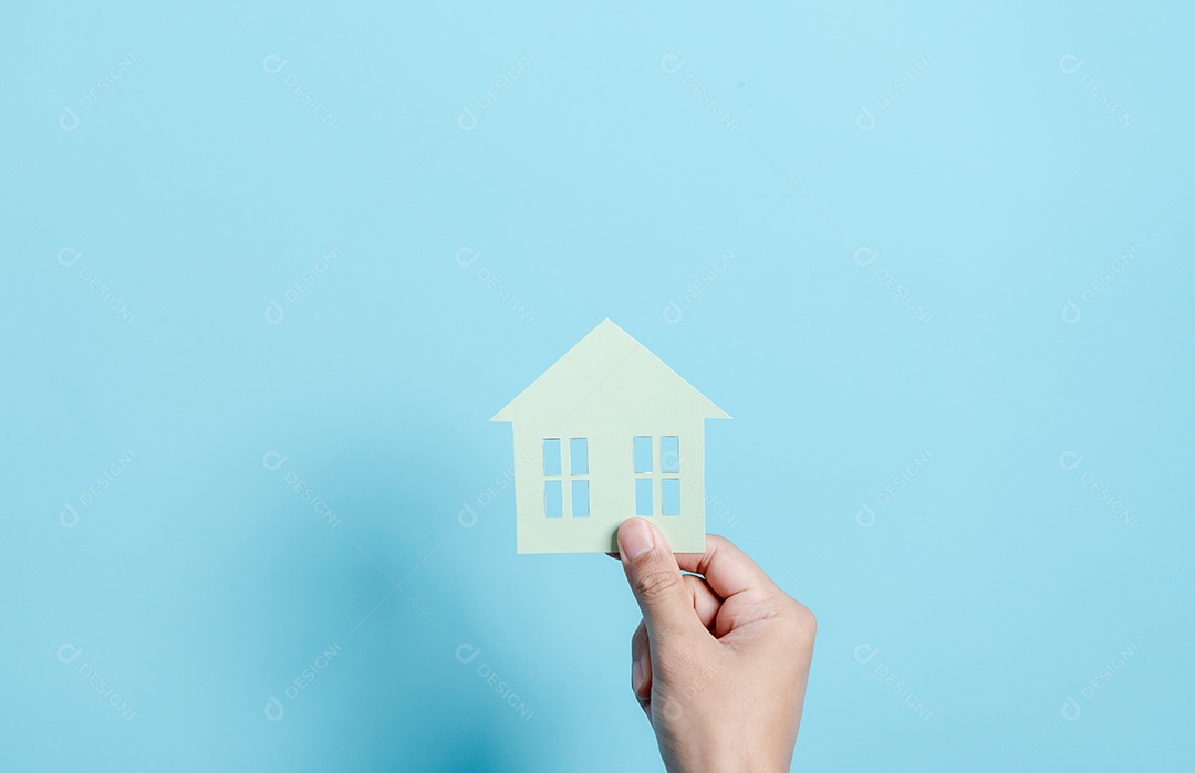 Mão segurando o corte de papel da casa, casa da família, habitação sem-teto, crise hipotecária e seguro de proteção residencial