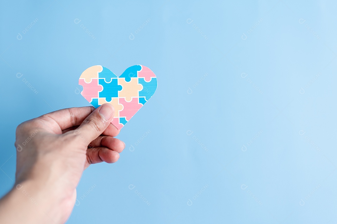 Mão segurando o quebra-cabeça do coração da consciência, símbolo de quebra-cabeça colorido de conscientização para o apoio à família do transtorno do espectro do autismo.