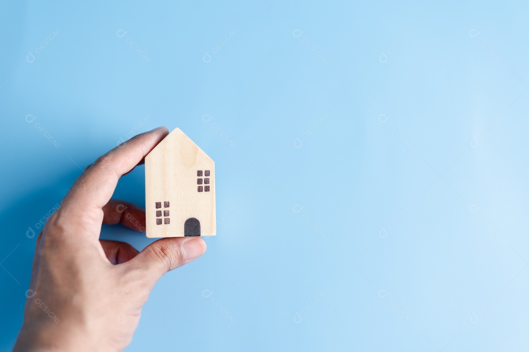 Mão segurando a casa de madeira, casa de família, habitação para sem-teto, crise de hipoteca e seguro de proteção residencial