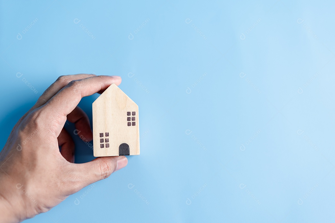 Mão segurando a casa de madeira, casa de família, habitação para sem-teto, crise de hipoteca e seguro de proteção residencial