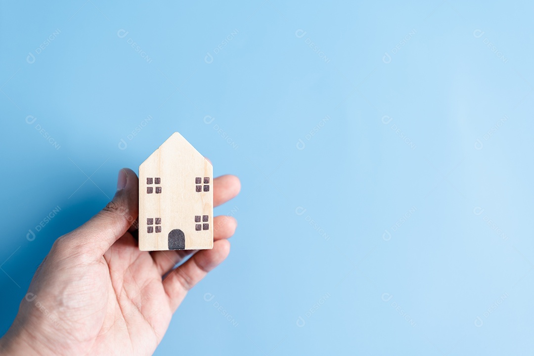 Mão segurando a casa de madeira, casa de família, habitação para sem-teto, crise de hipoteca e seguro de proteção residencial