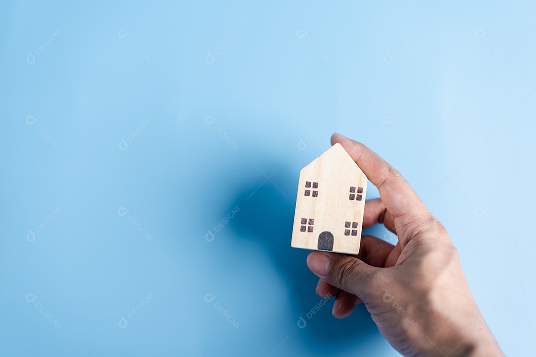 Mão segurando a casa de madeira, casa de família, habitação para sem-teto, crise de hipoteca e seguro de proteção residencial