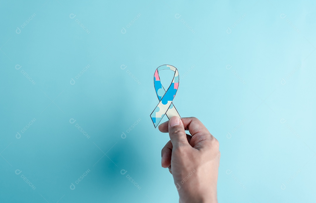 Mão segurando o quebra-cabeça da fita, símbolo de quebra-cabeça colorido de conscientização para o apoio à família do transtorno do espectro do autismo.