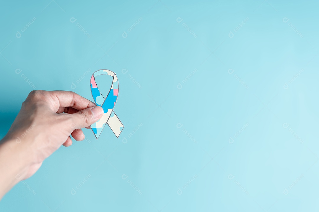 Mão segurando o quebra-cabeça da fita, símbolo de quebra-cabeça colorido de conscientização para o apoio à família do transtorno do espectro do autismo.