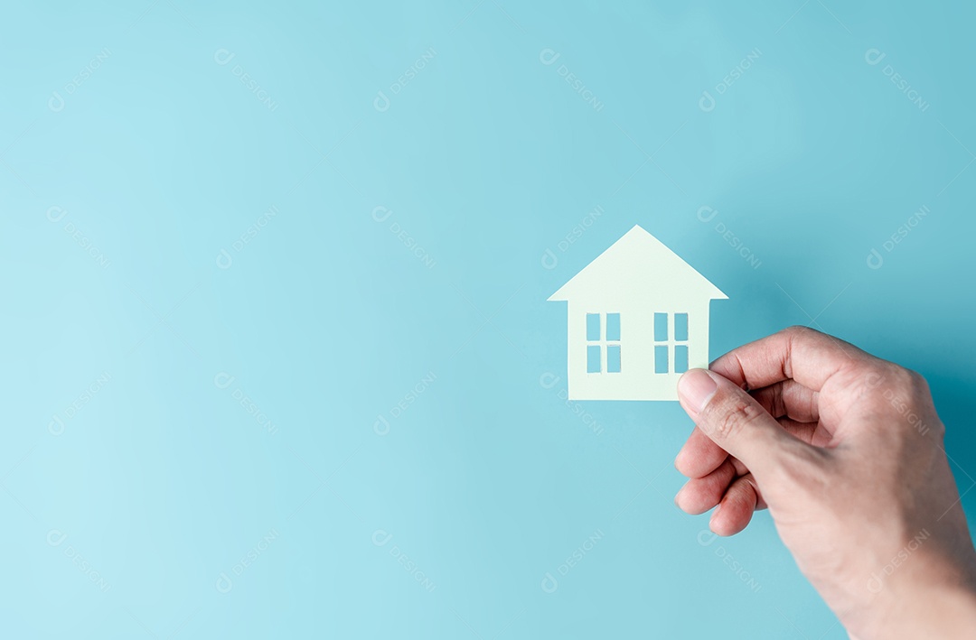 Mão segurando o corte de papel da casa, casa da família, habitação sem-teto, crise hipotecária e seguro de proteção residencial