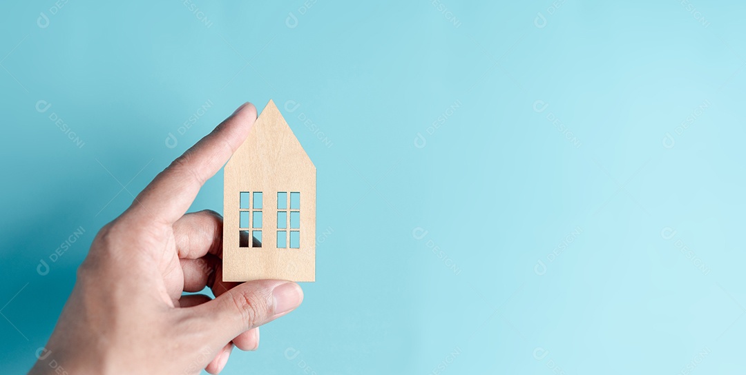 Mão segurando a casa de madeira, casa de família, habitação para sem-teto, crise de hipoteca e seguro de proteção residencial