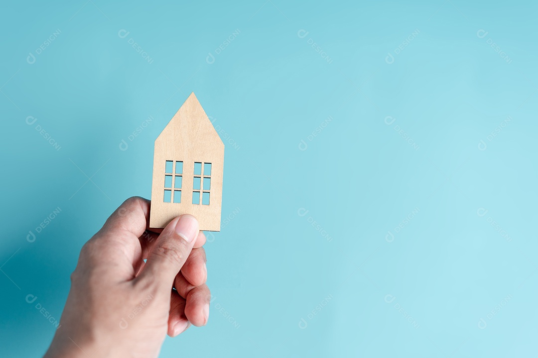 Mão segurando a casa de madeira, casa de família, habitação para sem-teto, crise de hipoteca e seguro de proteção residencial