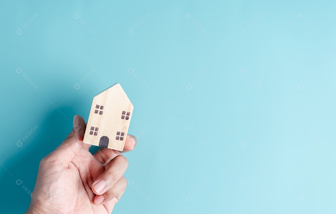 Mão segurando a casa de madeira, casa de família, habitação para sem-teto, crise de hipoteca e seguro de proteção residencial