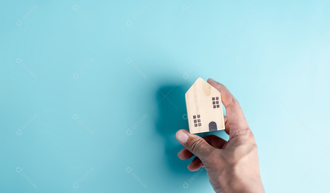 Mão segurando a casa de madeira, casa de família, habitação para sem-teto, crise de hipoteca e seguro de proteção residencial