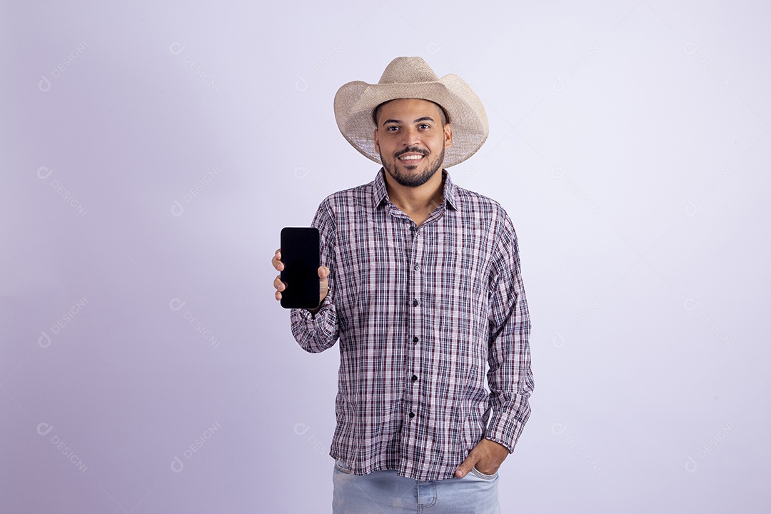 Homem jovem barbudo usando roupas de São João segurando celular smartphone