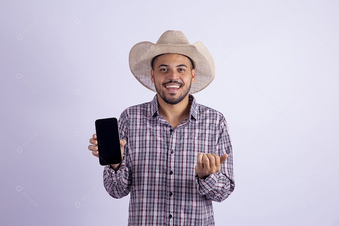 Homem jovem barbudo usando roupas de São João segurando celular smartphone