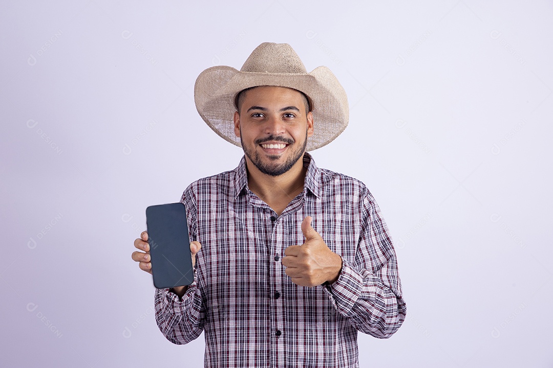 Homem jovem barbudo usando roupas de São João segurando celular smartphone