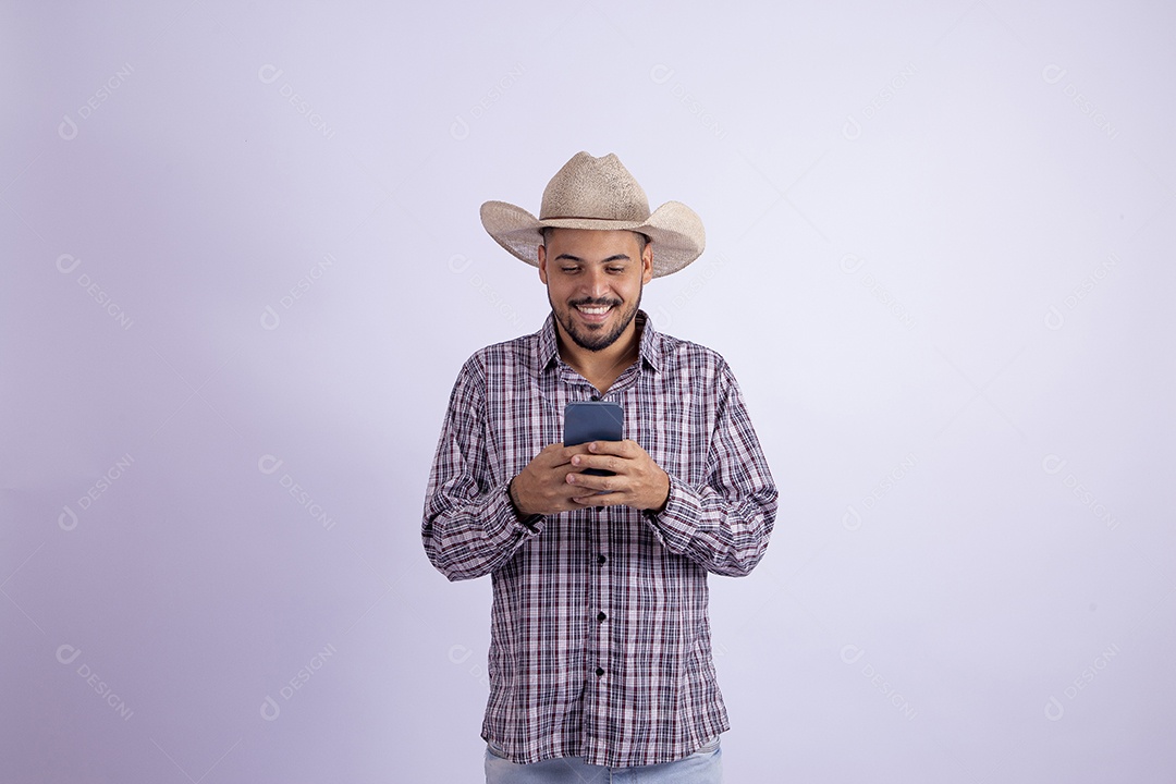 Homem jovem barbudo usando roupas de São João segurando celular smartphone