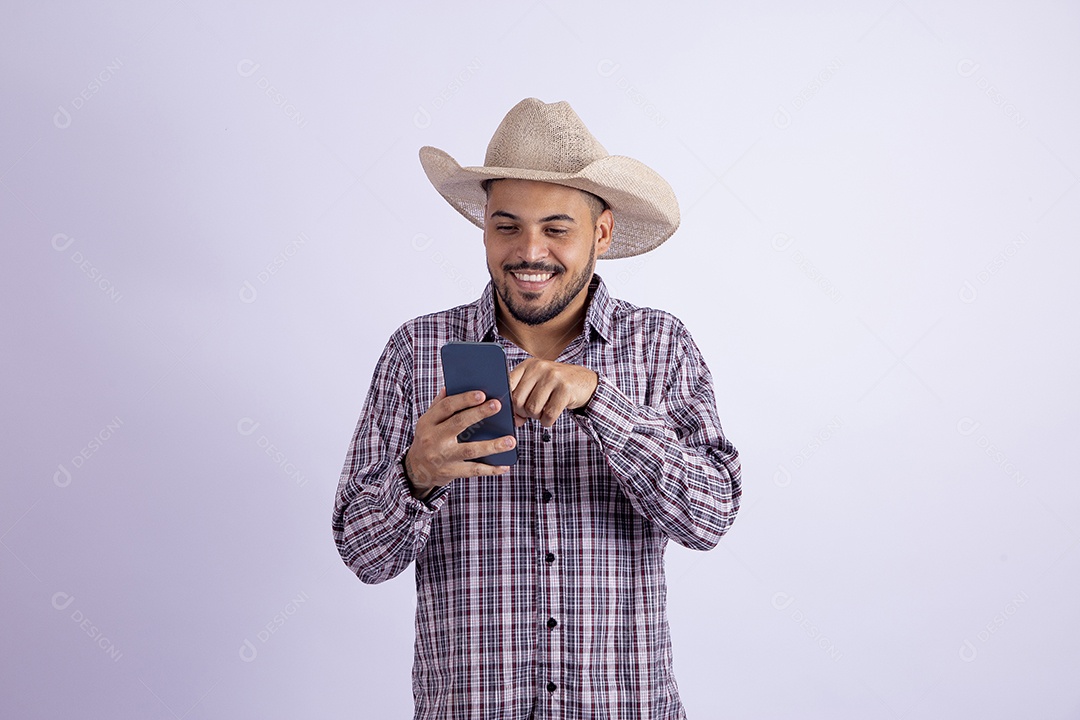 Homem jovem barbudo usando roupas de São João segurando celular smartphone
