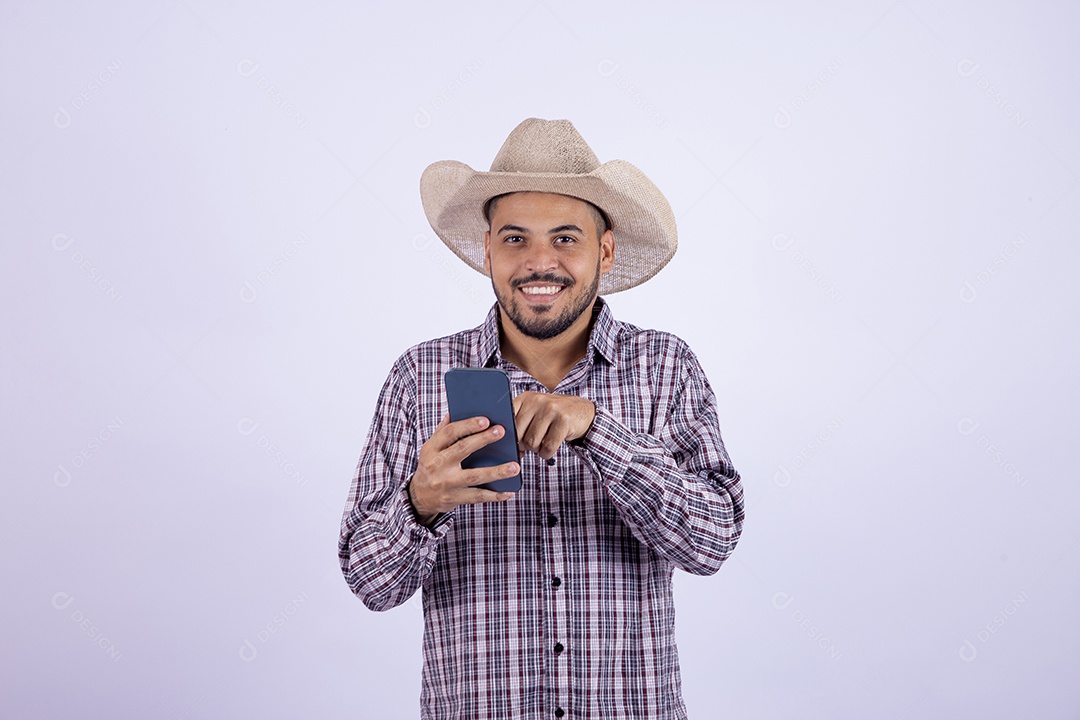 Homem jovem barbudo usando roupas de São João segurando celular smartphone