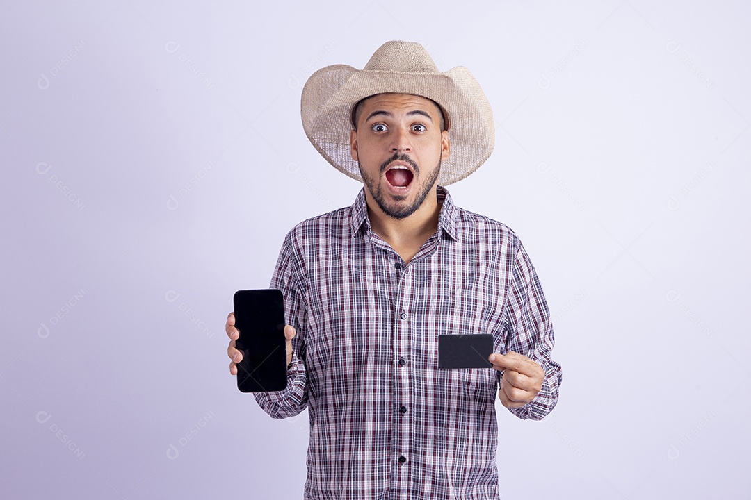 Homem jovem barbudo usando roupas de São João segurando celular smartphone e cartão de crédito